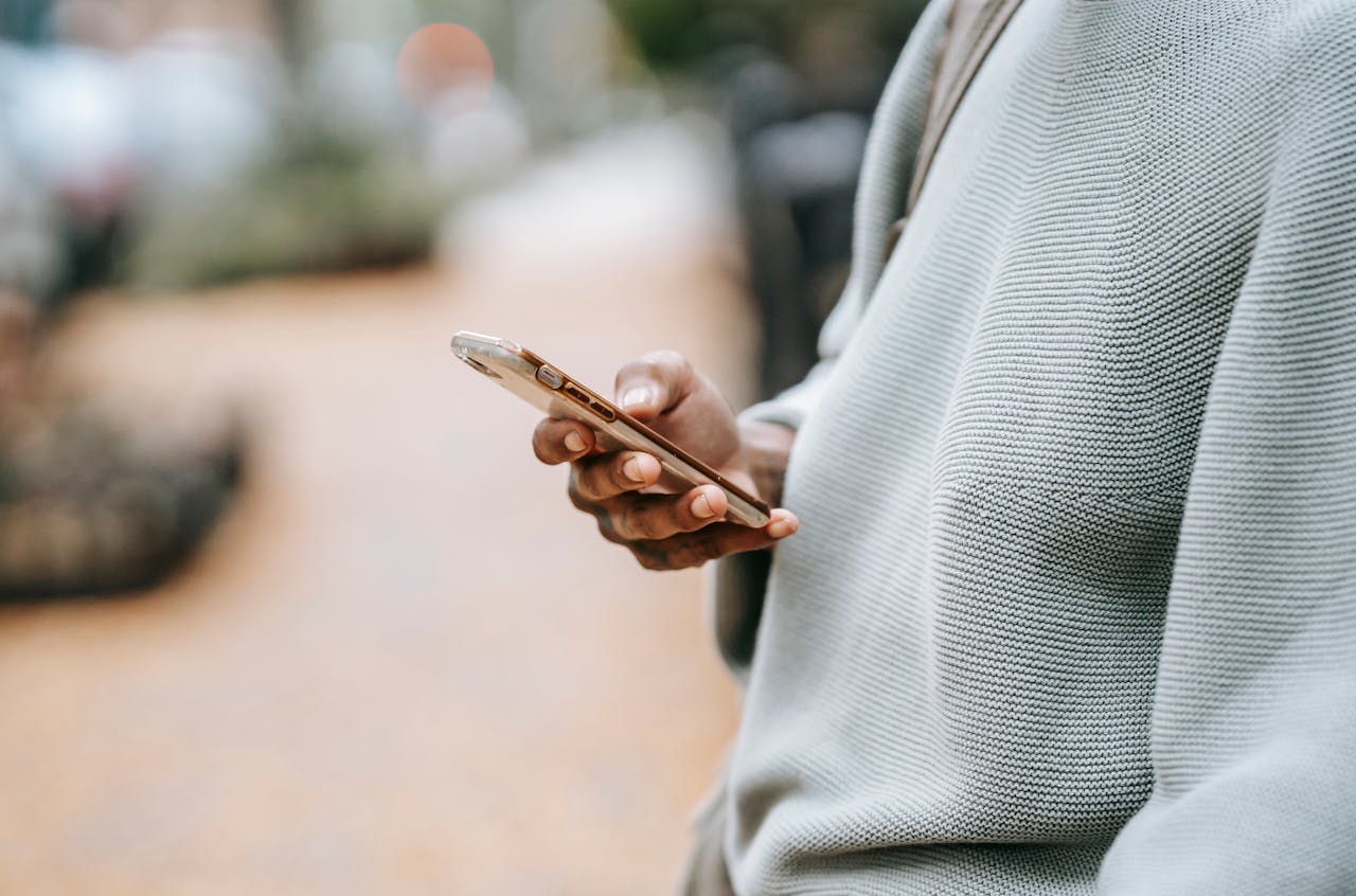 A person casually uses a smartphone outdoors in an urban environment, focusing on connection.